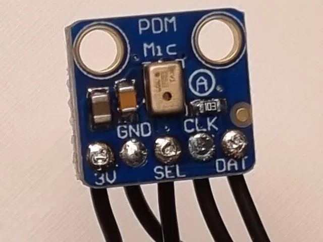 A small blue breakout board marked PDM Mic, with five soldered pads labelled 3V, GND, SEL, CLK and DAT and a black lead on each.